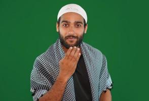 muslim boy saying hi using his traditional method Green screen background. photo