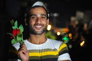 hombre guapo sosteniendo una rosa roja en la mano, en el techo foto