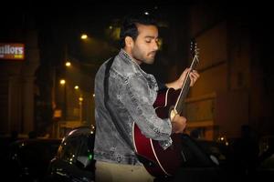 un guitarrista tocando su guitarra en la noche foto