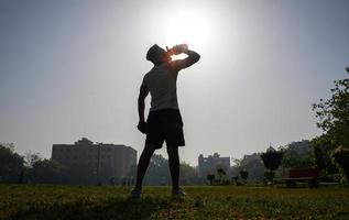 man at stedium over the silhouette image with shaker bottle for gym and drinking gainer -physical fitness concept photo