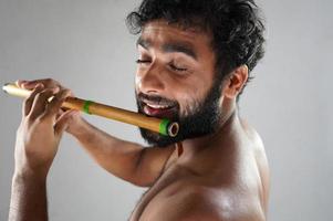 indian man playing flute with passion photo