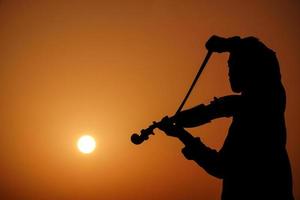 músico tocando violín. concepto de música y tono musical. imágenes de silueta de hombre músico foto