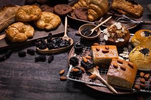 varios tipos de panadería y pan dulce con moras frescas y mermelada de moras sobre mesa de madera. surtido de pan horneado en un plato de madera oscura con espacio para copiar foto