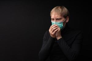 The masked man coughs. Symptoms of coronavirus. photo