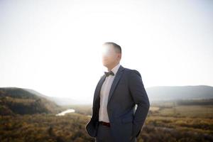 retrato de un guapo novio con traje en las montañas al atardecer. foto