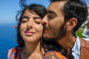 A man and a woman are hugging against the backdrop of Skaros Rock on Santorini Island. The village of Imerovigli. photo