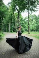 Young beautiful woman posing in a black dress in a park.