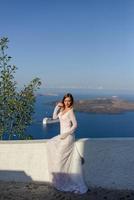 Beautiful bride In a white dress posing against the background of the Mediterranean Sea in Thira, Santorini. photo