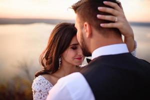 The bride and groom are walking near the old castle. The couple stands with their backs to each other. photo