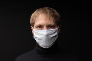 A man in a medical mask looks at the camera. Shot on a black background. photo