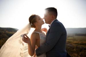 Portrait of a young beautiful bride and her husband in the mountains with a veil. The wind develops a veil. Wedding photography in the mountains. photo