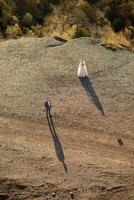 Wedding photo session of the bride and groom in the mountains. Photoshoot at sunset.Shot from above from a high angle.