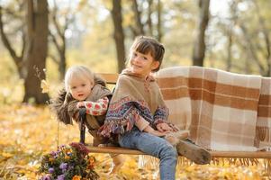 Two sisters are sitting on a bench in an autumn park. photo