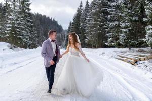 The groom leads his bride by the hand to a lonely old beech. Winter wedding. Place for a logo. photo