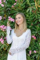 Portrait of a beautiful bride in a white dress in a bush of flowers. photo