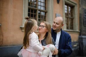 Parents and their daughter are sitting on the steps of an old church. photo