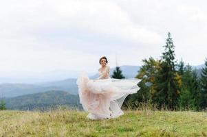 The bride in a pink airy dress swirls and plays with her dress. photo