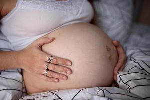 A pregnant girl clings to her belly and worries before giving birth during a krantin. Self-isolation at home. photo