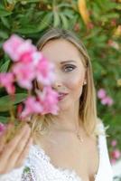 Portrait of a beautiful bride in a white dress in a bush of flowers. photo