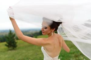 The bride and groom hug under a veil and gently bowed their heads to each other. photo