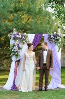 Evening photo session of the bride and groom near the wedding arch after the ceremony