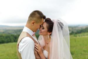 The bride and groom hug under a veil and gently bowed their heads to each other. photo