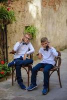 dos niños pequeños, los hermanos están vestidos con traje. los niños están parados en el parque y abrazándose. foto