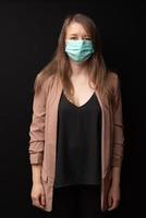 Young woman in a mask. Coronavirus protection. Shot on a black background photo