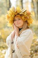 Autumn portrait of a beautiful middle-aged woman. The woman painted herself a fan of leaves. Autumn photo shoot.