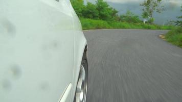 Beside white car driving and goes on asphalt road. Trip travel to upcountry go with a green natural environment. atmosphere before rain. curve back and forth on the mountain. video