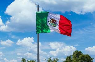 los cabos, méxico, bandera tricolor mexicana a rayas ondeando orgullosamente en el mástil en el aire con el símbolo azteca de tenochtitlan foto