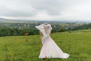 The bride and groom hug under a veil and gently bowed their heads to each other. photo