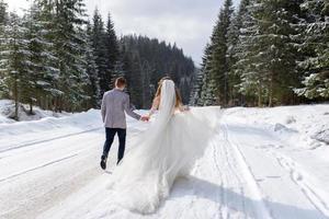 The groom leads his bride by the hand to a lonely old beech. Winter wedding. Place for a logo. photo