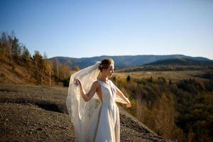 Portrait of a young beautiful bride in the mountains with a veil. The wind develops a veil. Wedding photography in the mountains. photo