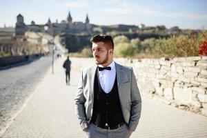 The bride and groom are walking near the old castle. The couple stands with their backs to each other. photo