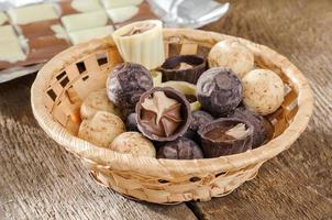 bombones y chocolate en una cesta sobre una mesa de madera foto