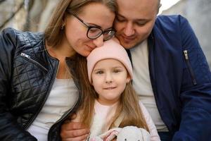 Parents and their daughter are sitting on the steps of an old church. photo