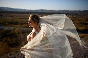 retrato de una joven novia hermosa en las montañas con un velo. el viento desarrolla un velo. fotografía de boda en la montaña. foto