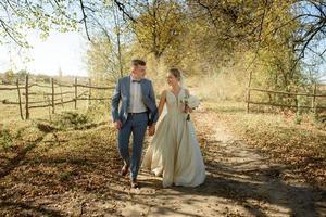 una pareja joven y hermosa camina con sus vestidos de novia en un parque de otoño. foto