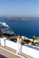 Beautiful bride In a white dress posing against the background of the Mediterranean Sea in Thira, Santorini.