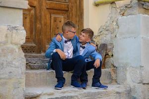 Two little boys, brothers are dressed in a suit. Children are standing in the park and hugging. photo