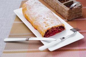 rollo casero con mermelada en un plato blanco con tenedor y cuchillo foto