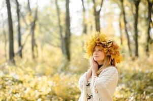 Autumn portrait of a beautiful middle-aged woman. The woman painted herself a fan of leaves. Autumn photo shoot.