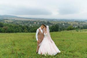 The bride and groom hug under a veil and gently bowed their heads to each other. photo