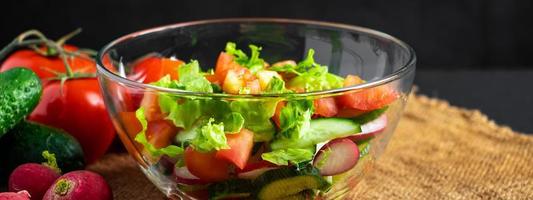 ensalada de verduras frescas en un recipiente de vidrio sobre fondo oscuro. comida organica vegana foto
