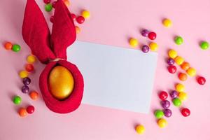 huevos de pascua dorados brillantes y tarjeta de felicitación en blanco sobre fondo rosa. foto