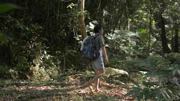 mujer viajera con mochila caminando por la jungla y disfrutando de ver hermosos paisajes de la cascada.