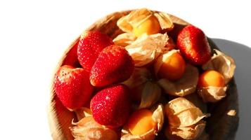 Strawberry and cape gooseberry in betel palm plate isolated on white background. photo