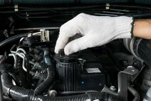 Un mecánico está abriendo el tapón de aceite del motor de un automóvil. foto