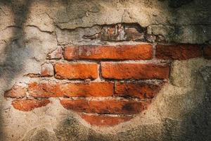 The surface of the old wall is so broken that the bricks inside can be seen. photo